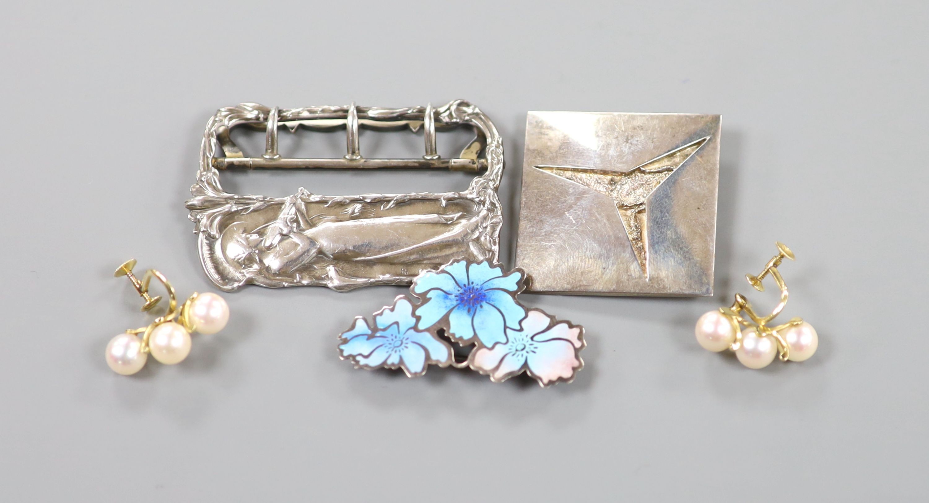 A French Art Nouveau style white metal buckle, a pair of 14k yellow metal and cultured pearl cluster set ear clips, a sterling and enamel brooch and one other silver brooch.